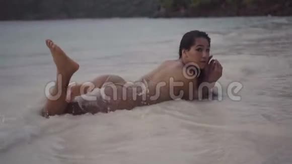 女孩躺在沙子上溅水和在缓慢的运动中感觉的移动的视频视频的预览图