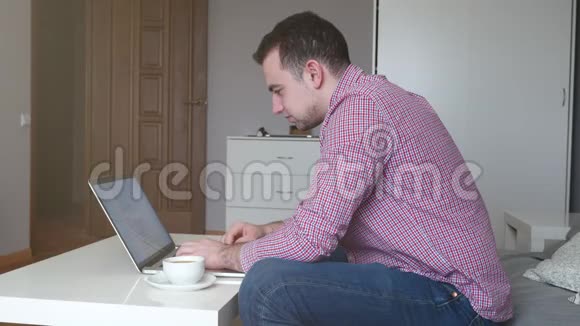 在家工作的人使用顶部和触控板年轻的商人坐在桌子上喝咖啡做工作视频的预览图