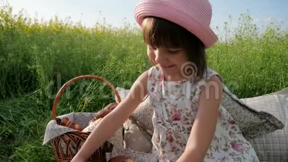 野餐周末鲜花草地上的女孩带着糕点和牛奶快乐的孩子鲜花草地上可爱的女孩带着视频的预览图