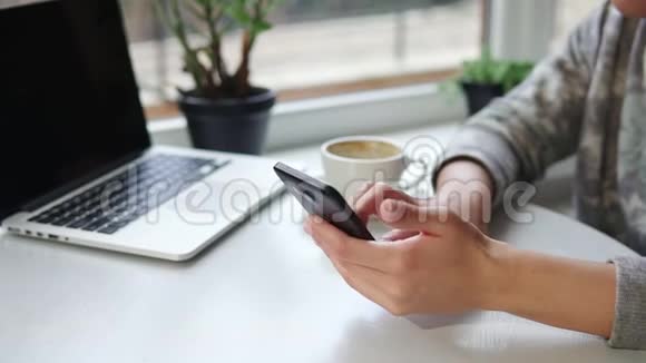 女人在智能手机上使用应用程序在咖啡馆里喝咖啡微笑着在手机上发短信美丽的年轻女性视频的预览图