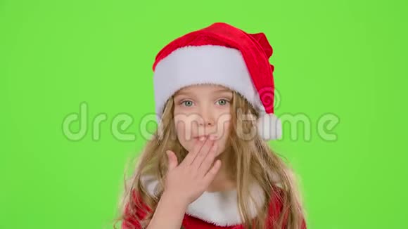 戴着红色圣诞帽的小女孩送空气亲吻绿色屏幕视频的预览图
