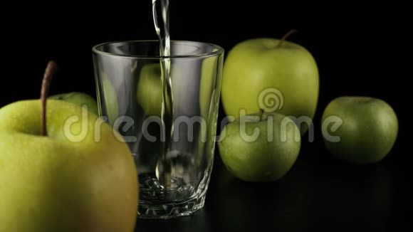 慢动作苹果汁倒入黑色背景的玻璃杯中视频的预览图
