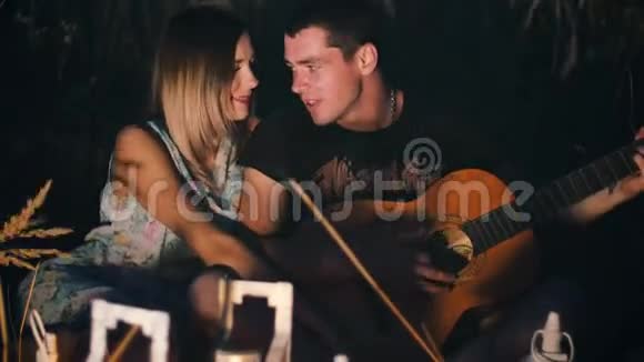 男人用吉他唱一首歌给他的女朋友晚上在田野里用蜡烛灯笼视频的预览图