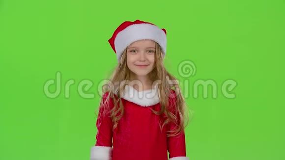 戴着红色圣诞帽的小女孩送空气亲吻绿色屏幕视频的预览图