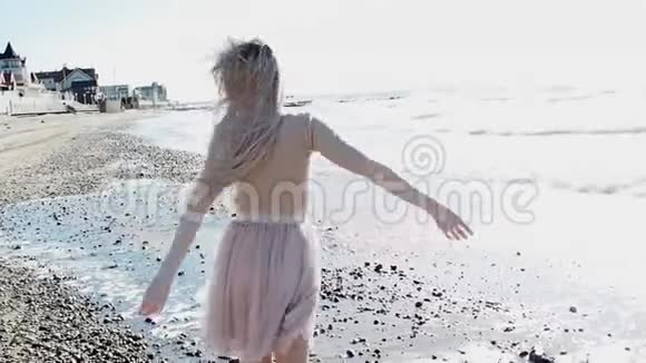 海边的年轻活泼的女孩年轻的金发女人微笑张开双臂拥抱海洋视频的预览图