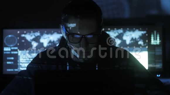 男性黑客程序员在计算机上工作而蓝码字符在网络安全中心反射他的脸视频的预览图