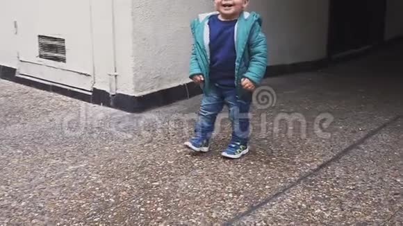 一个穿夹克的小男孩沿着院子里的小路跑慢动作视频的预览图