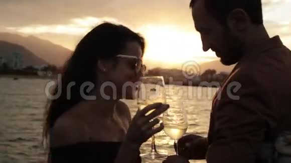 带着酒杯的年轻夫妇在游船甲板上聊天喝酒视频的预览图