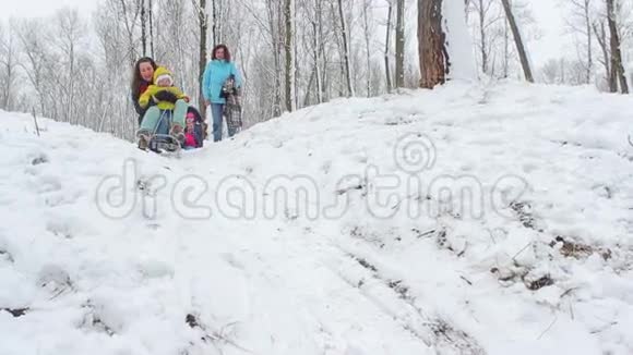 妈妈和一个小女孩骑着雪橇从山上下来视频的预览图