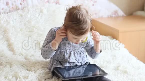 有趣的快乐孩子手拿平板电脑戴着耳机视频的预览图