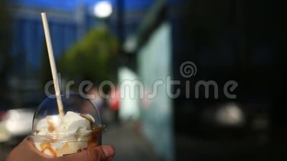 一个男人在街上吃快餐他带着奶昔和鲜奶油吃在这样的背景下视频的预览图