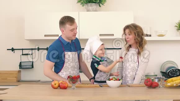 儿子用草莓招待父母他们在厨房准备一份水果沙拉视频的预览图