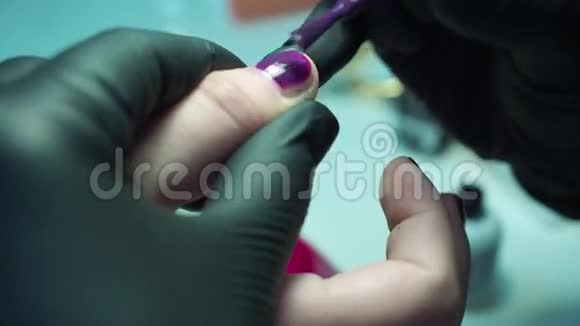 专业的美甲师在美容院用黑色手套修指甲深紫色漂亮的粉红色指甲近距离拍摄视频的预览图