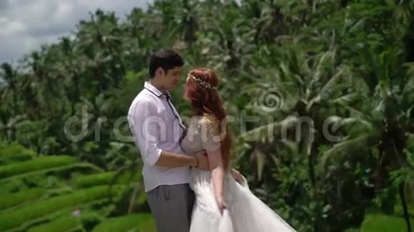 新婚夫妇在巴厘岛的米台上摆姿势牵手拥抱浪漫的婚礼视频的预览图