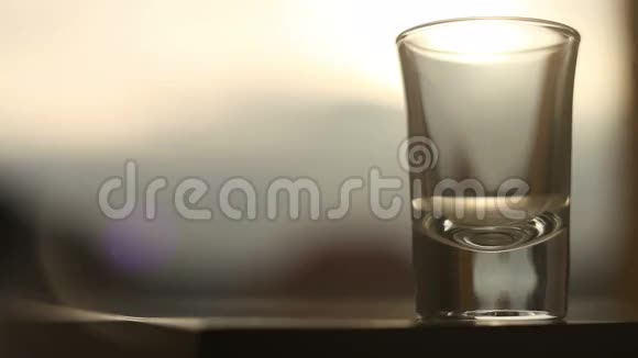 在夕阳的背景下向玻璃上倒一杯金色的饮料视频的预览图