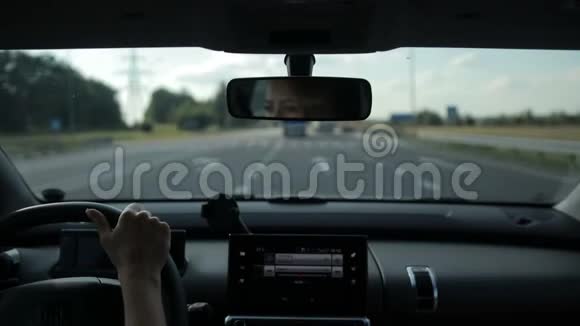 年轻女子在阳光下驾车行驶在高速公路上视频的预览图