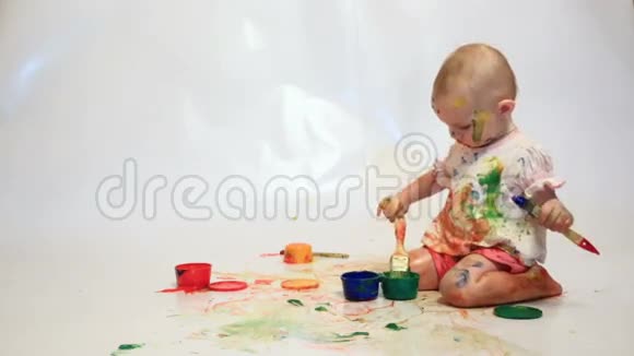 被油漆弄脏的婴儿拿着刷子视频的预览图