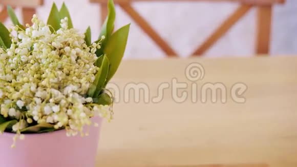 一张木桌上放着一束山谷的百合花视频的预览图