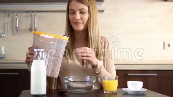漂亮的年轻漂亮的女人在厨房里用碗里倒玉米片做早餐视频的预览图