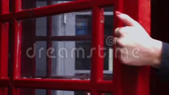 年轻的红发女人试图走出电话亭视频的预览图