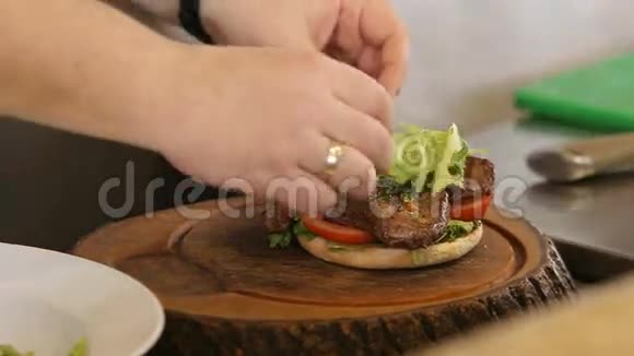 厨师把绿生菜叶放在汉堡肉上视频的预览图