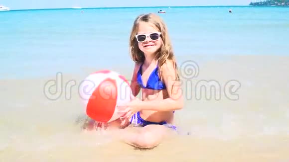 穿着蓝色比基尼坐在海里玩水球的女孩视频的预览图