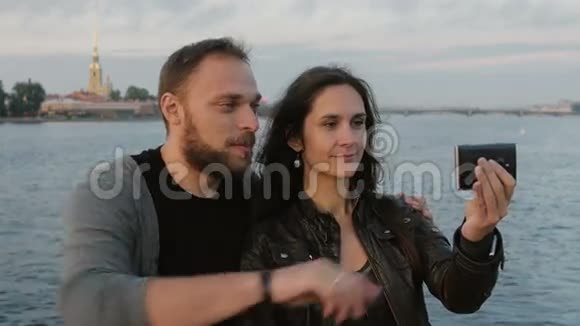 美丽的年轻夫妇在河流和城市的背景下自拍彼得堡和保罗堡4K视频的预览图