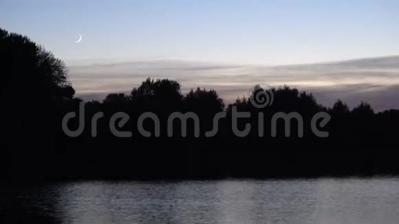 黄昏时分湖上有一个月牙背景是森林轮廓分明视频的预览图