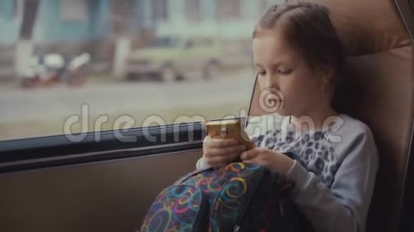年轻漂亮的女乘客在移动校车上带着书包在她的智能手机和社交网络上使用社交网络视频的预览图