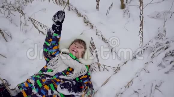 冬天公园里一个非常可爱快乐的小男孩冬天的时候快乐的男孩在雪地公园玩得开心他很高兴视频的预览图