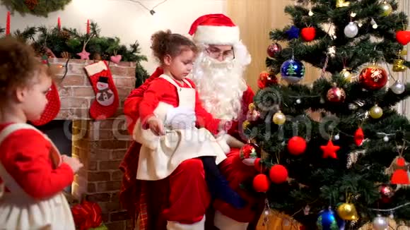 圣诞老人带着一个孩子在房间里装饰一棵圣诞树和圣诞装饰品视频的预览图