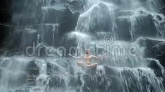 男子坐在瑜伽姿势的背景瀑布视频的预览图