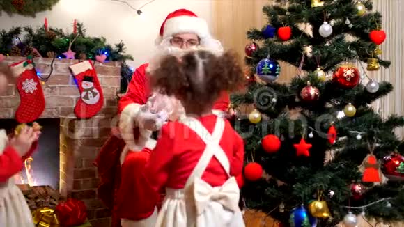 圣诞老人带着一个孩子在房间里装饰一棵圣诞树和圣诞装饰品视频的预览图