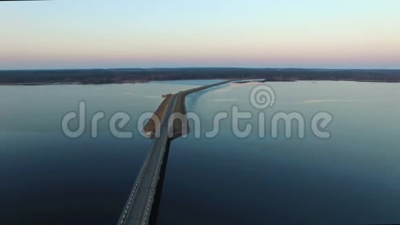 4K日落时飞越冰冻的大湖冬天有桥鸟瞰视频的预览图