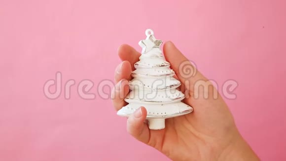 简单的最小设计女性手拿圣诞装饰杉树隔离粉红色的粉彩色彩视频的预览图