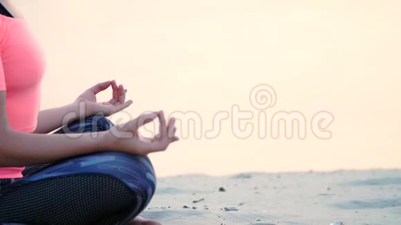 健康年轻的美丽女子冥想在海滩上练习瑜伽海边日出时放松肌肉放松心灵视频的预览图