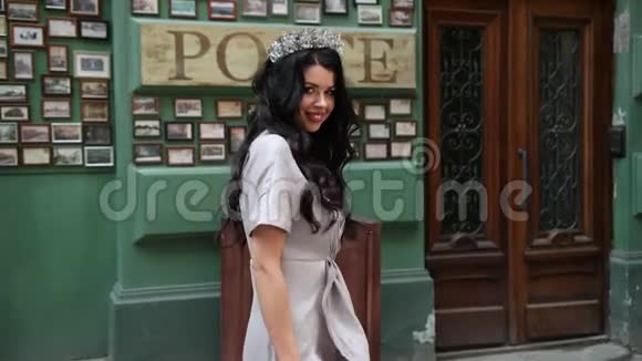 布吕内特女孩穿着灰色连衣裙双腿修长妆容鲜艳头戴皇冠摆姿势视频的预览图