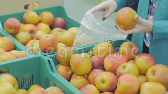 超市里的女人来到水果柜台她选择把苹果放进塑料袋里视频的预览图
