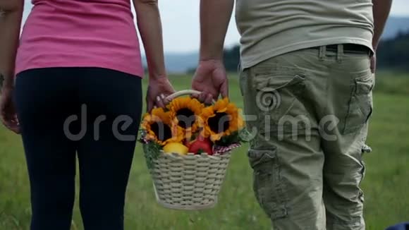一对夫妇拿着白色篮子和向日葵离开镜头视频的预览图