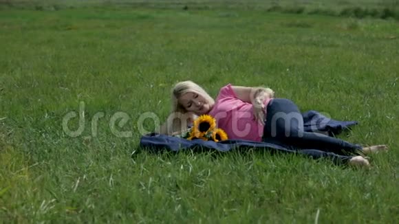 女人抚摸着她的胃躺在毯子上拿着向日葵花束视频的预览图