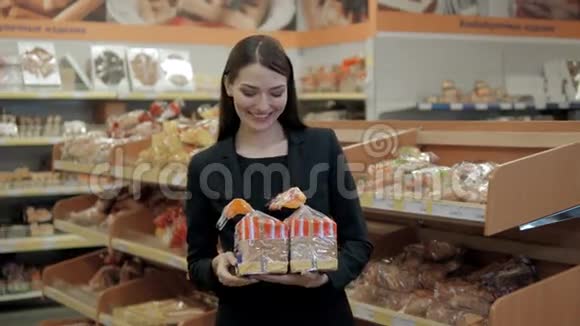 女人在超市里吃面包快乐的黑发女人吃面包视频的预览图