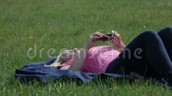 女人摘下墨镜躺在阳光下的草地上视频的预览图