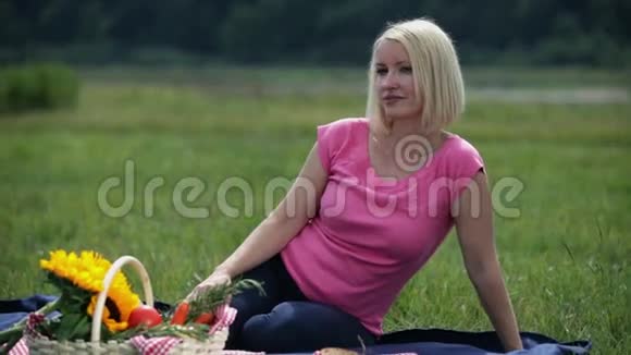 躺在野餐毯上的女人坐着环顾四周视频的预览图