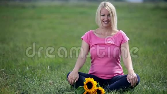 微笑的年轻女性坐在莲花的位置在大自然中视频的预览图