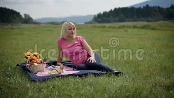 女人一边看一边躺在野餐毯上拿着东西视频的预览图