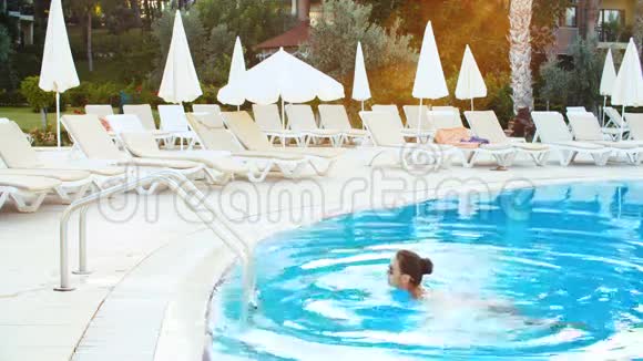 阳光明媚的夏日身着比基尼和太阳镜的年轻黑发女子走出游泳池视频的预览图