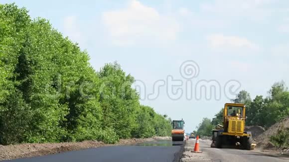 修复一条公路压路机和沥青修整机铺设一条新的新鲜沥青路面覆盖在一条公路上视频的预览图