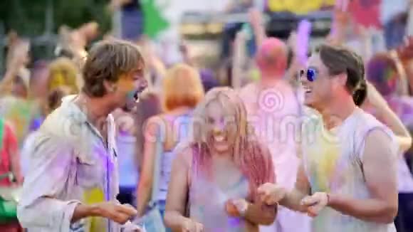 快乐的年轻人在空中撒着五颜六色的粉末在节日里跳舞视频的预览图