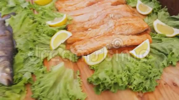 烤红鲑鱼加沙拉在美食节的餐桌上放着蔬菜和柠檬的煮熟的鱼片视频的预览图