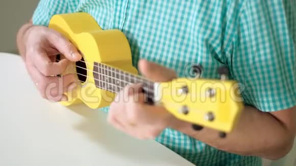 一个人在黄色的四弦琴上演奏视频的预览图